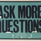 Picture hanging on wall saying: "ASK MORE QUESTIONS"