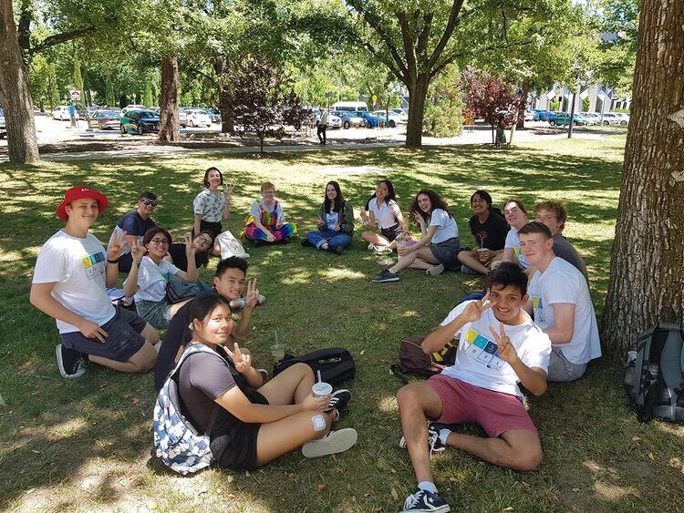 2021 NYSF Year 12 Program participants sitting in a circle on the grass underneath some trees.
