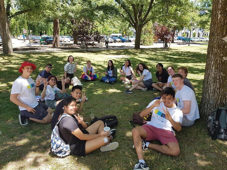 2021 NYSF Year 12 Program participants sitting in a circle on the grass underneath some trees.